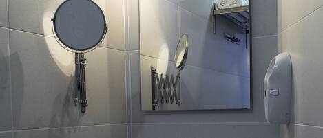 A modern bathroom with a round mirror, a sink, and a towel rack.