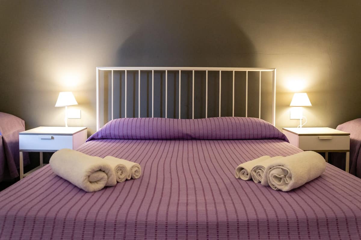 Una habitación de hotel con una cama grande, dos mesitas de noche y dos lámparas.