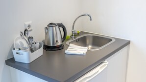 A kitchen counter with a kettle, a sink, and a dish rack. - NXT PARK Hamburg by ANS (Hamburg)