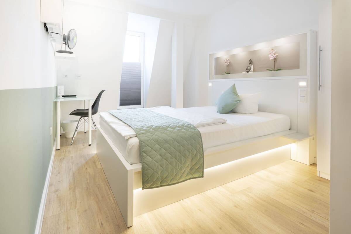 Um quarto moderno com cama, mesa de cabeceira, cadeira e escrivaninha com cadeira.