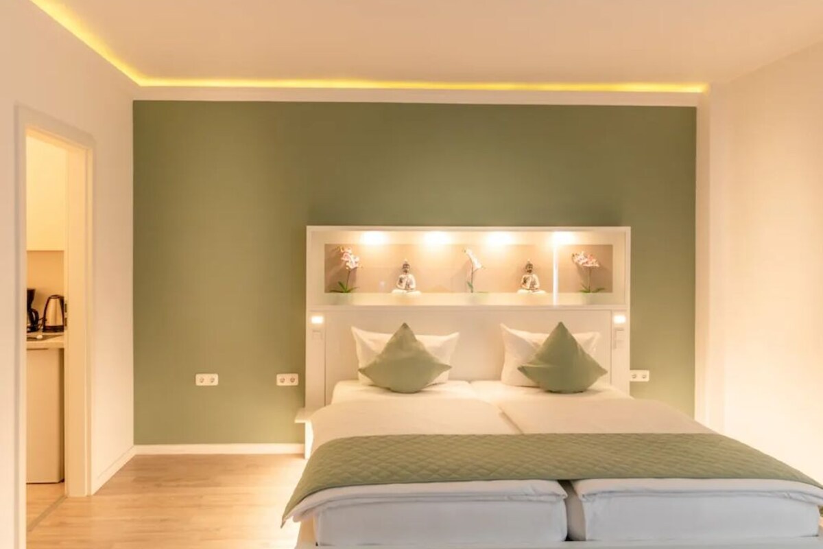 Een slaapkamer met een bed, nachtkastjes en een wandplank met decoratieve objecten.