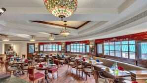 A spacious restaurant with wooden floors, multiple dining tables, and ornate chandeliers. - Club Mahindra White Meadows Manali (Manali)
