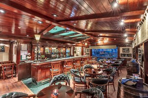 Zona de bar con mobiliario de madera, una barra y un ventanal con vistas a la ciudad.