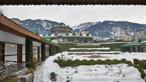 A traditional building with a green roof, surrounded by snow-covered gardens and mountains in the background. - Club Mahindra White Meadows Manali (Manali)