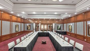 Un salón de conferencias con una larga mesa, sillas y piso alfombrado.