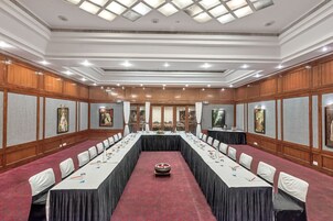 Un salón de conferencias con una larga mesa, sillas y piso alfombrado.