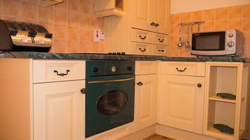 A kitchen with white cabinets, a green oven, a microwave, and a toaster.