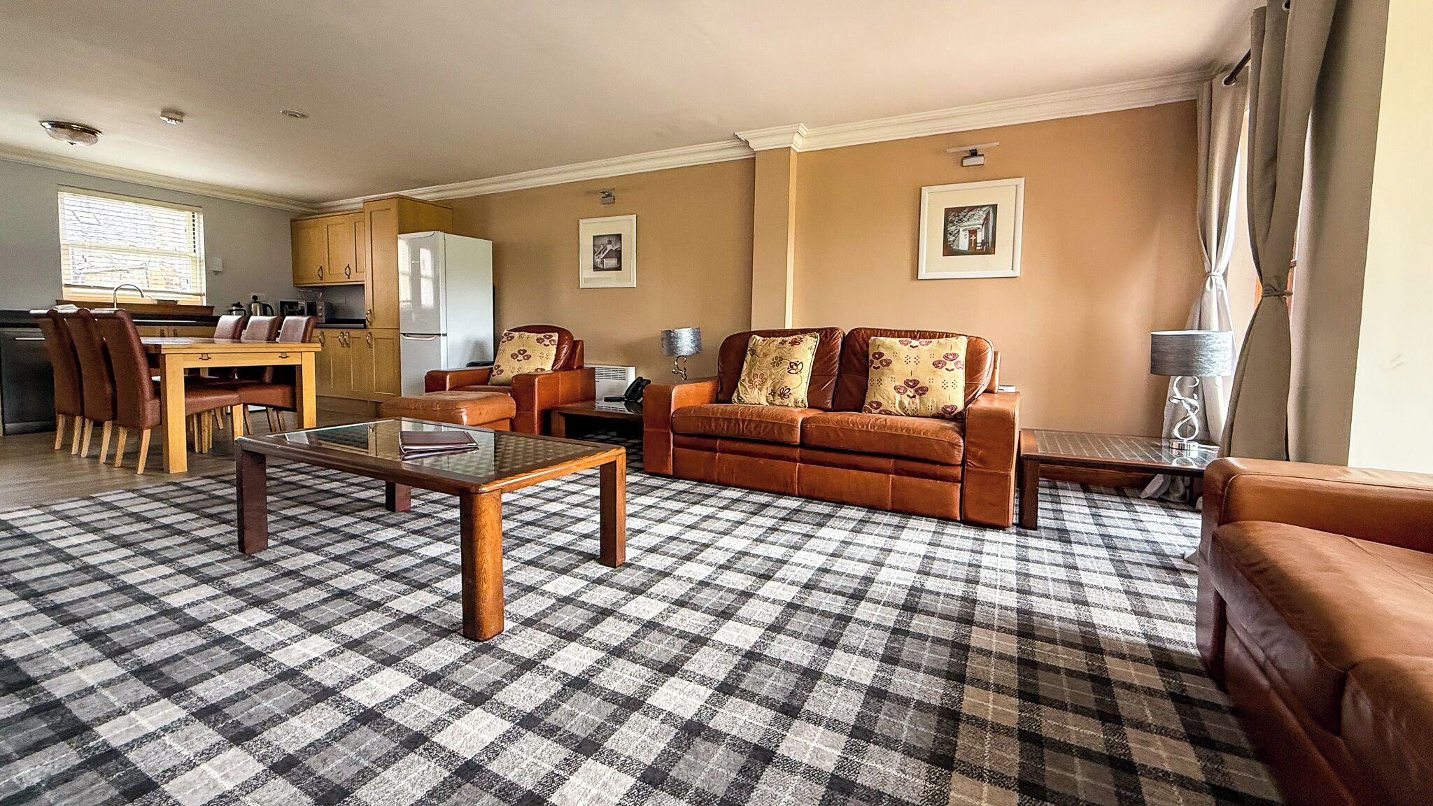 A living room with a checkered carpet, a sofa, a coffee table, and a dining area with chairs and a table.