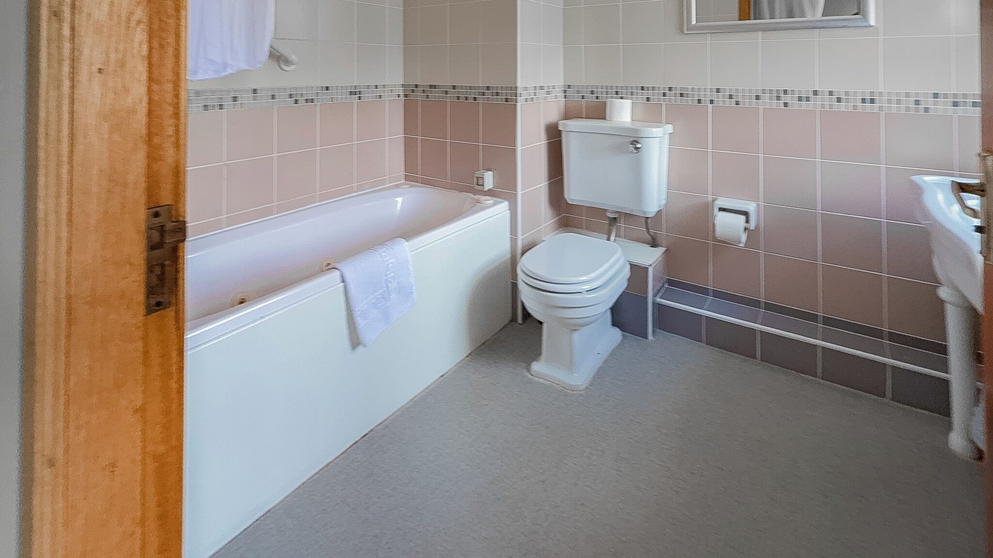 A bathroom with a bathtub, toilet, and a small window above the toilet.