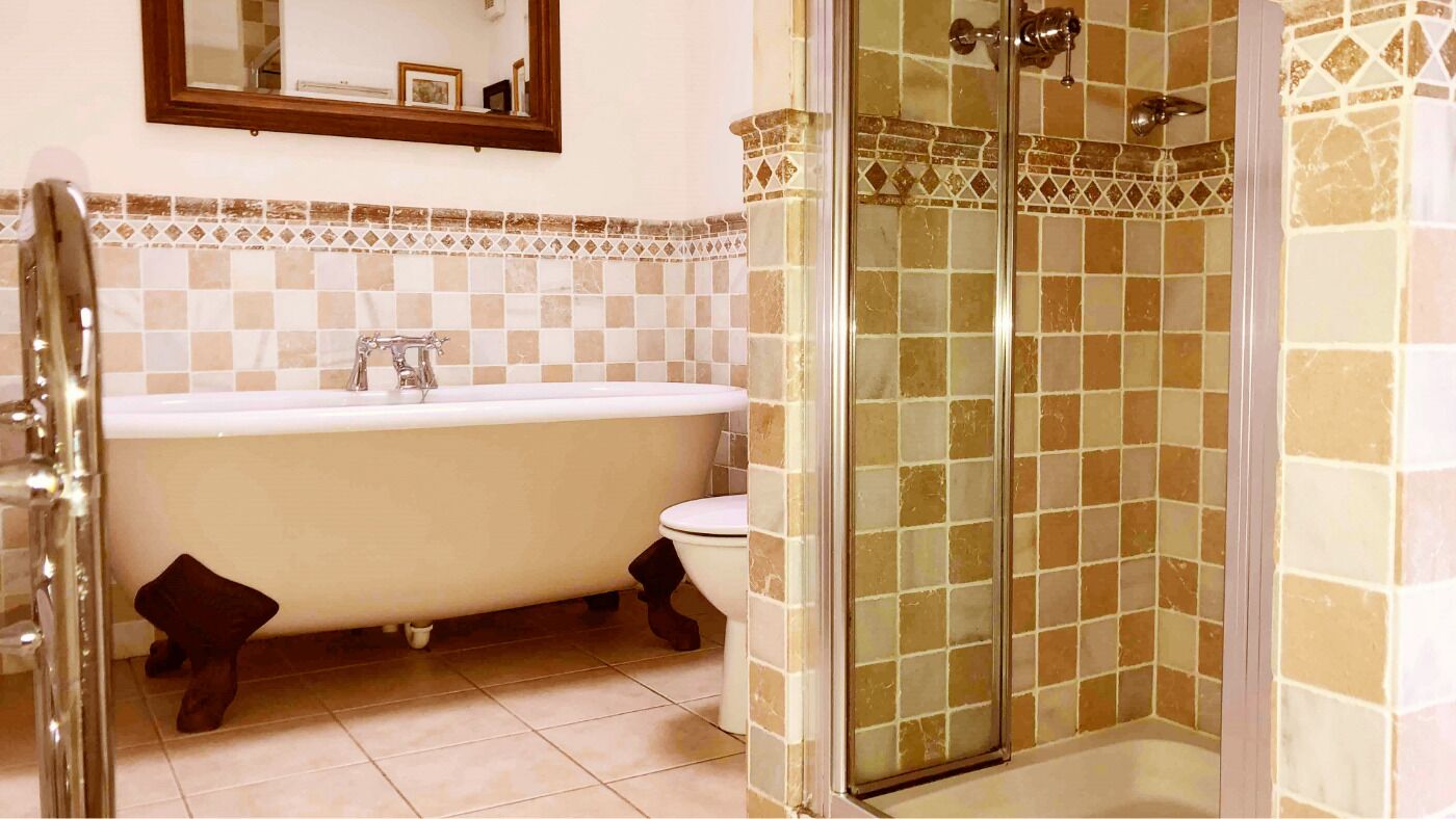 A bathroom with a bathtub, toilet, and a shower with a glass door.