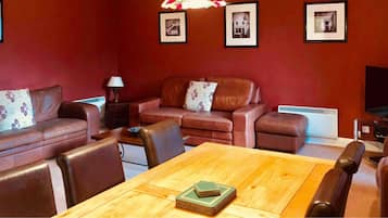 Een gezellige woonkamer met een bruine leren bank, een houten salontafel en een televisie.