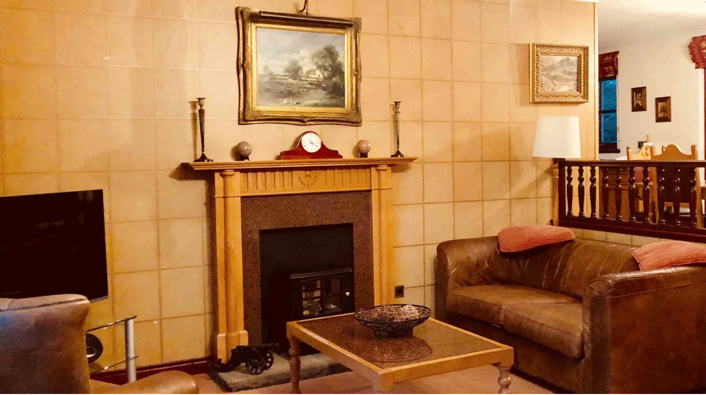 A living room with a fireplace, a sofa, a coffee table, and a television.