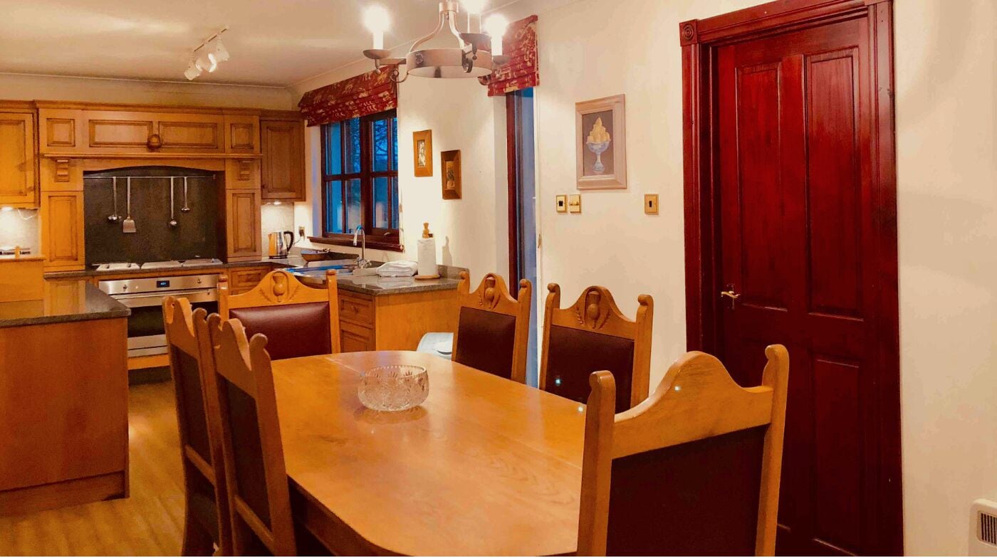 Cucina con mobili in legno, un tavolo da pranzo e sedie.