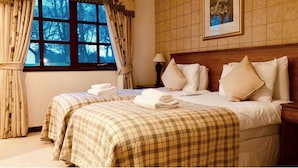 A hotel room with two beds, checkered bedding, a window with curtains, a lamp, and a framed picture on the wall. - Kilconquhar Castle Estate (Leven)