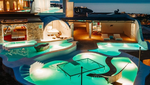 Un resort lujoso con una amplia piscina infinita, un área de spa y vistas al océano.