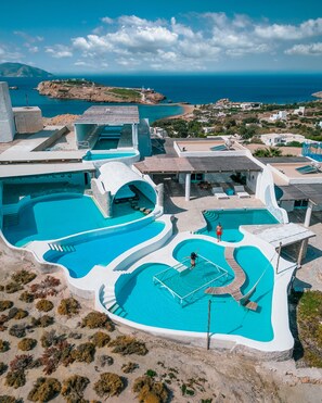 A resort with multiple swimming pools, a lighthouse, and a view of the sea. - Agalia Luxury Suites (Ios)