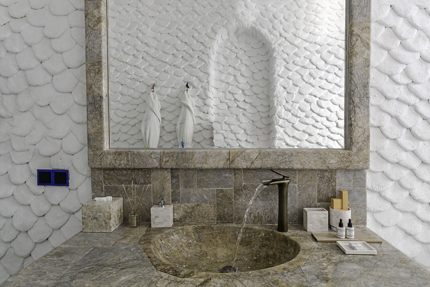 Un bagno con uno specchio grande, un lavabo in pietra e una parete in marmo.