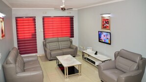 A living room with two sofas, a coffee table, and a TV on the wall. - Riverside Hotel and Conference Centre (Lilongwe)