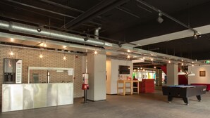 A spacious indoor area with a pool table, a reception desk, and a brick wall. - WOW Hostel Amsterdam (Amsterdam)
