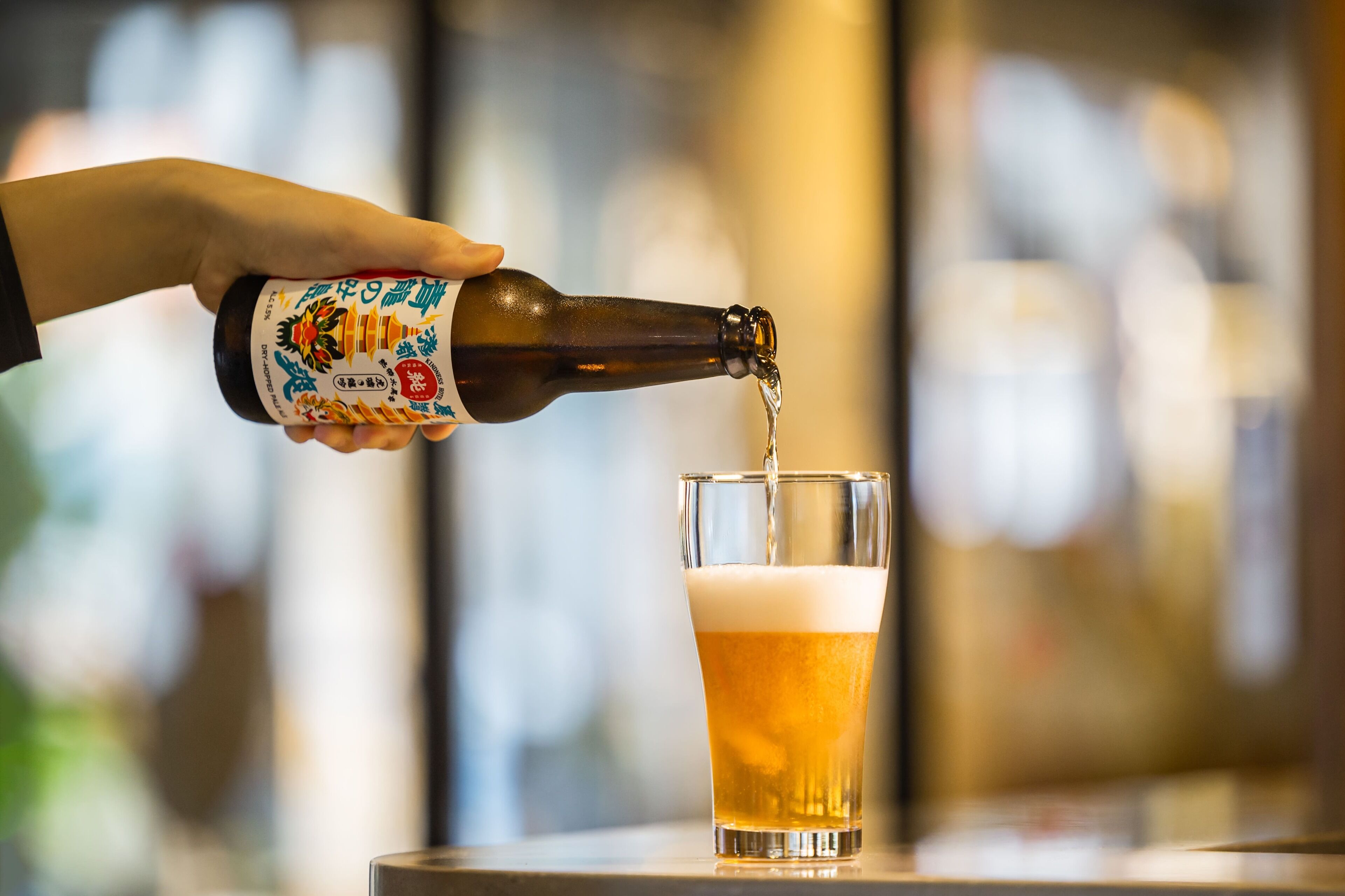 Una mano sirviendo cerveza en un vaso.