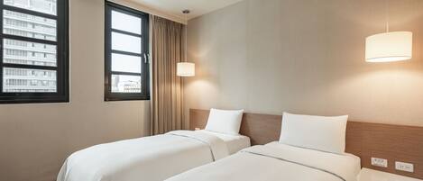 Habitación de hotel con dos camas, una ventana con cortinas, una lámpara de pared y un cabecero de madera.