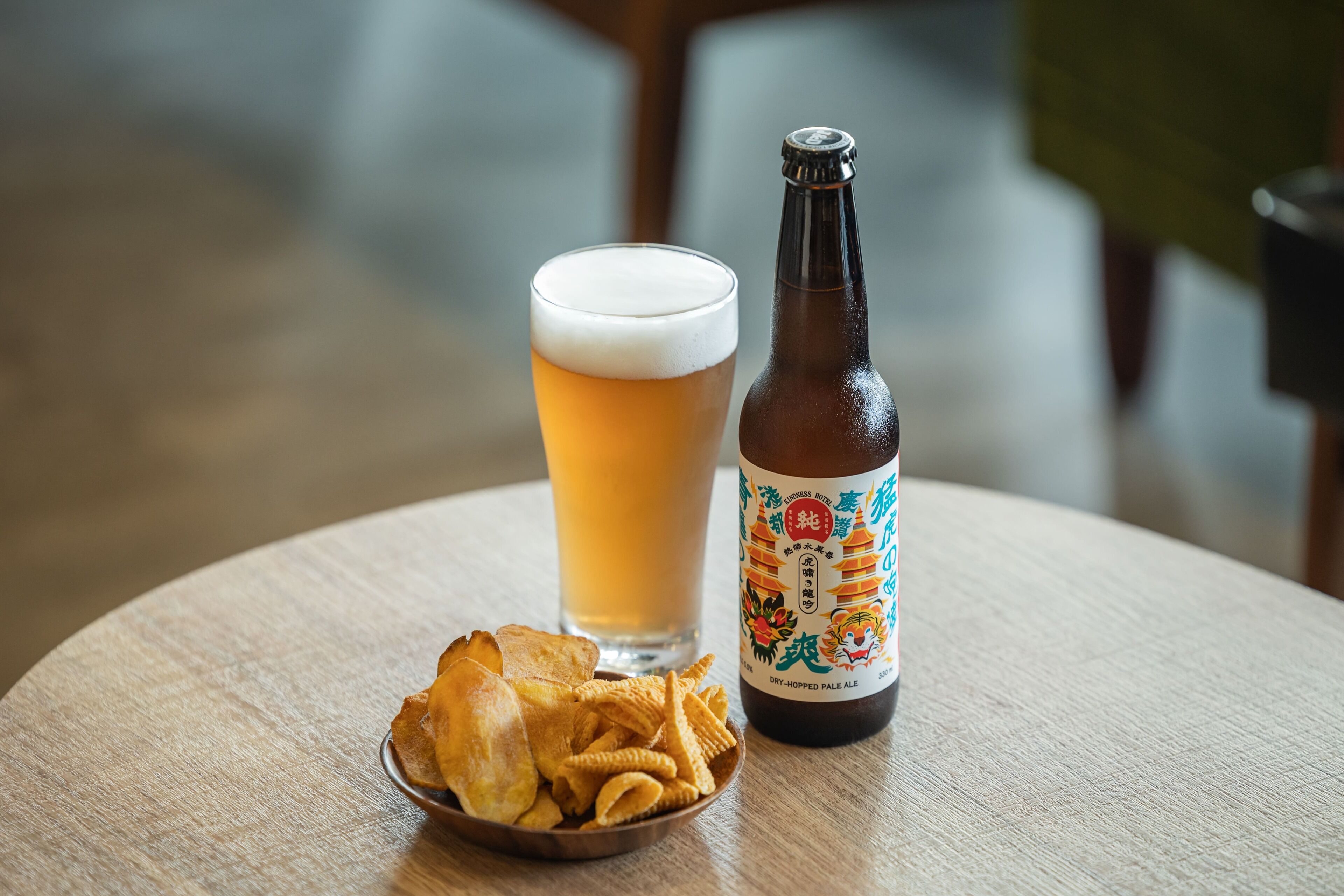 A bottle of beer and a glass of beer on a round table.