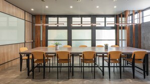 Een congreszaal met een lange tafel, meerdere stoelen en hanglampen.