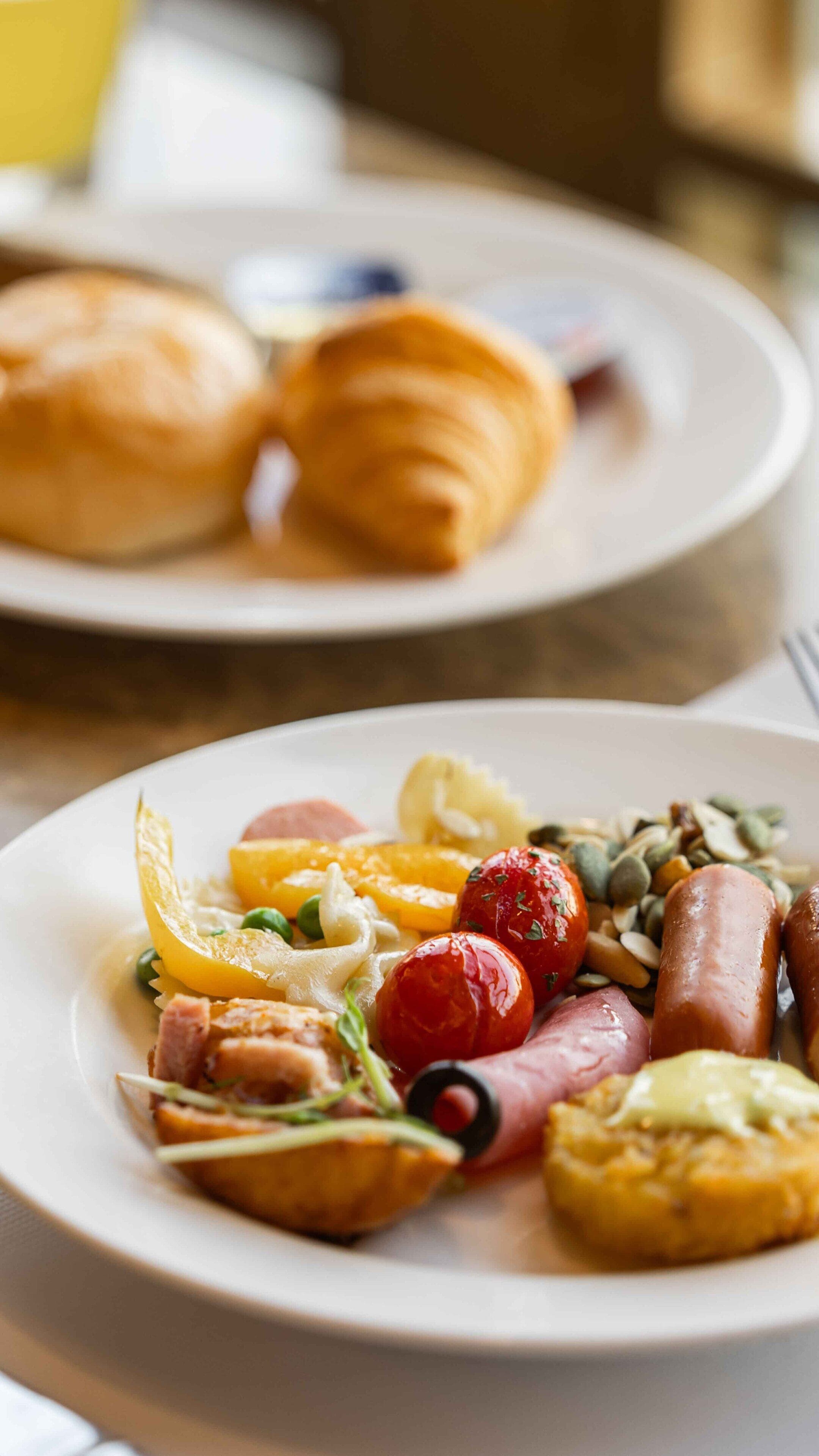 A breakfast setting with plates of food including eggs, sausages, and vegetables.
