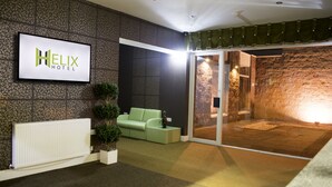 A Helix Hotel reception area with a modern design, including a reception desk, a green sofa, and a large window overlooking the interior. - Helix Hotel (Grangemouth)