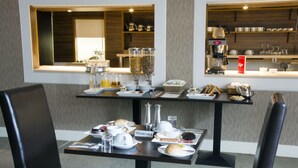 A breakfast buffet setup with various food items, beverages, and dining ware on tables. - Helix Hotel (Grangemouth)