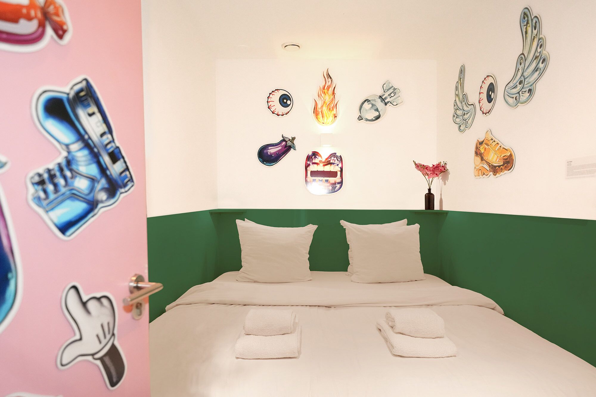A bedroom with a green headboard, two white pillows, and a bed with white linens.
