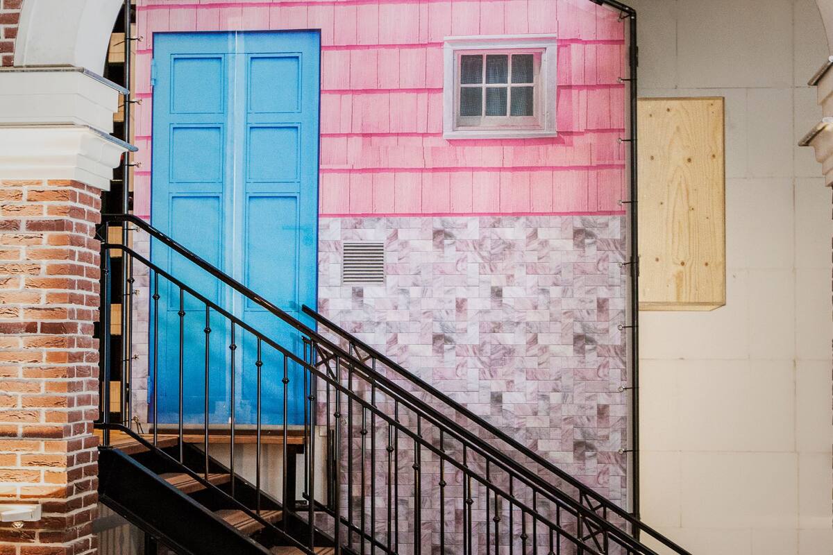 A staircase leading to a pink and blue door, with a wooden table in the foreground.