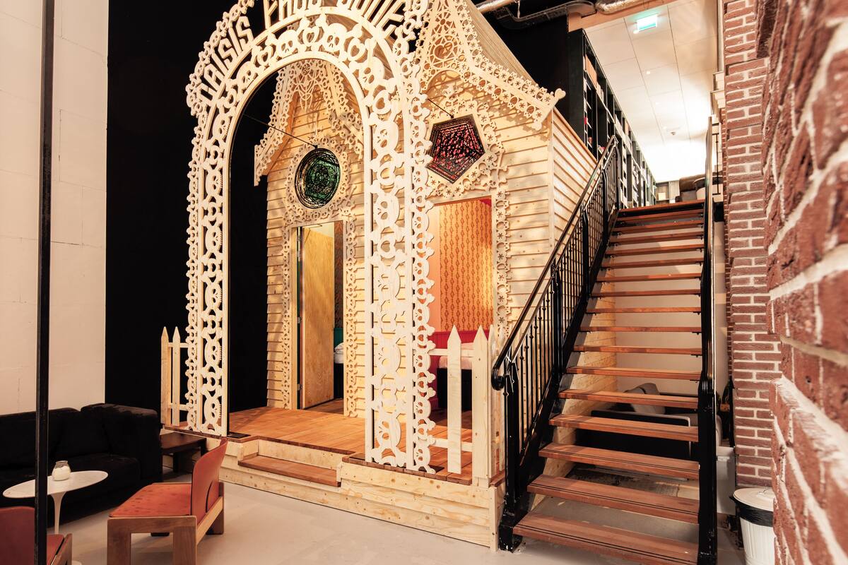 A wooden structure with intricate carvings, a staircase, and a small seating area with a table and chairs.