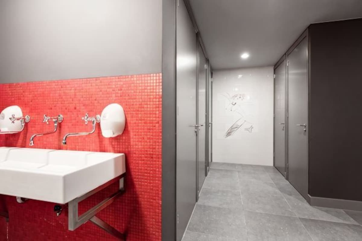 Un bagno moderno con una parete piastrellata di rosso, un lavandino bianco e uno specchio.
