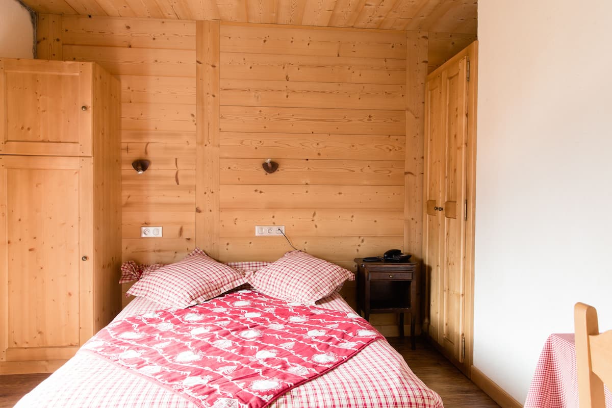 A wooden-paneled room with a bed, a nightstand, and a wardrobe.