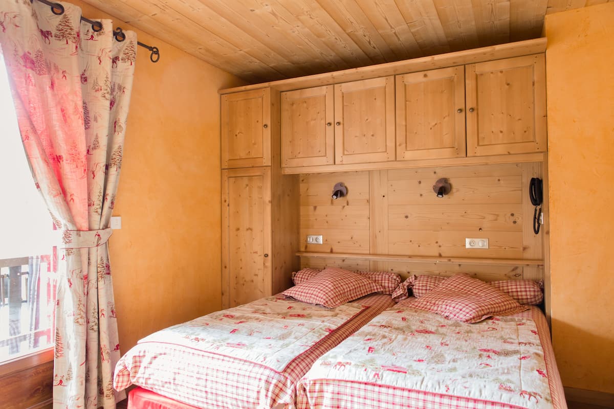 A bedroom with a wooden headboard, a bed with floral bedding, and a curtain with a tree pattern.
