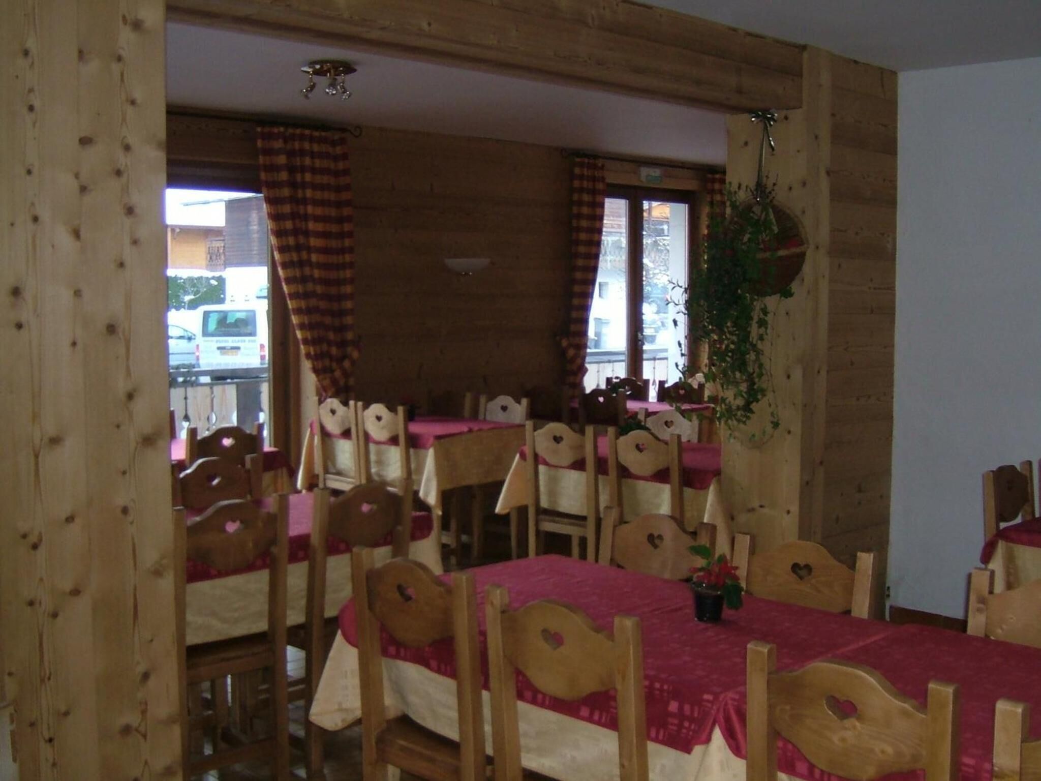Un espace repas avec des tables et des chaises en bois, chacune dotée d’un appui-tête en forme de cœur.