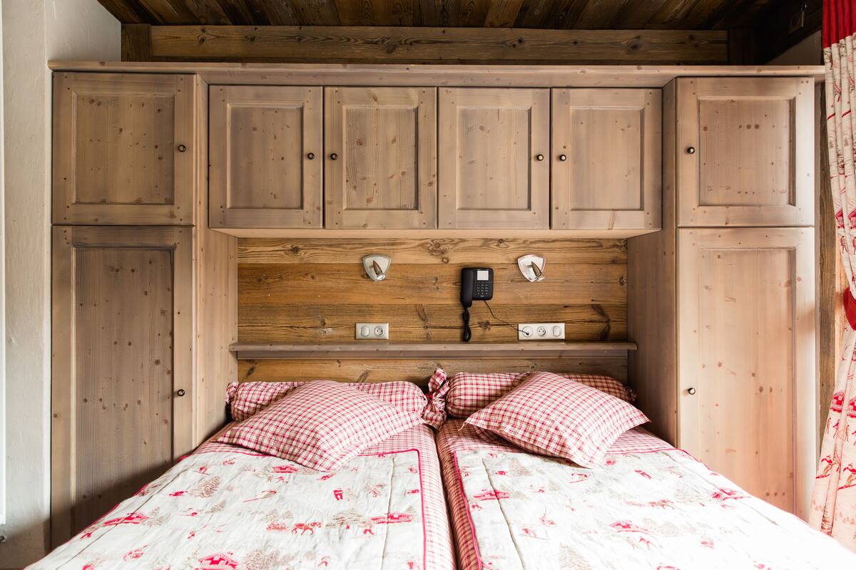 A bedroom with a wooden headboard, a telephone, and a bed with checkered bedding.