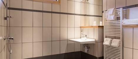 A modern bathroom with a shower, sink, and toilet.