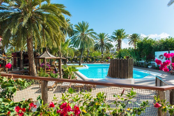 A pool area with palm trees, a gazebo, and a fenced deck.