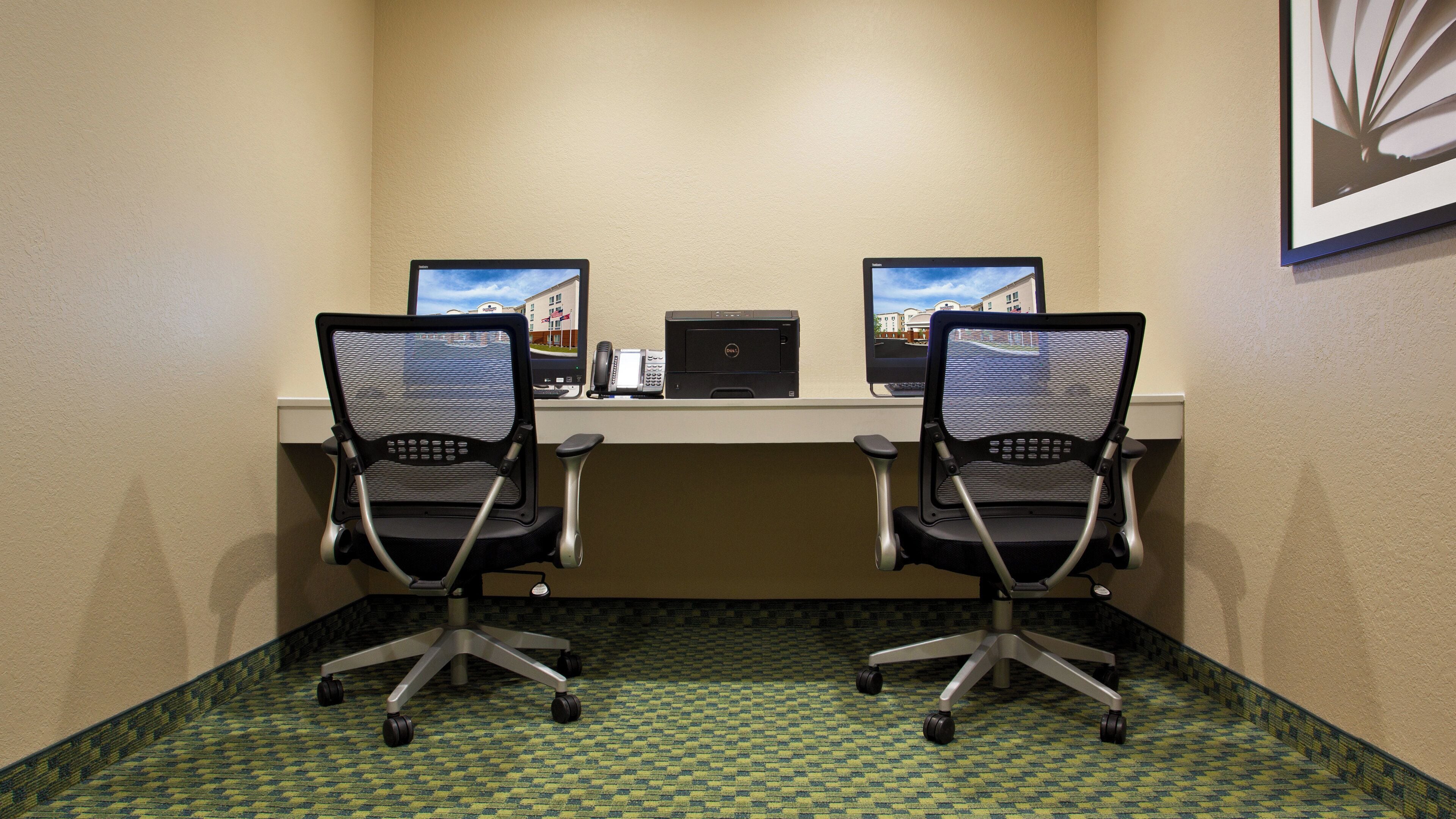 A room with two office chairs, a desk, and a computer.
