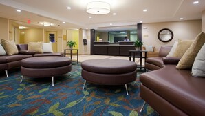 A hotel lobby with leather sofas, a reception desk, and a patterned carpet.