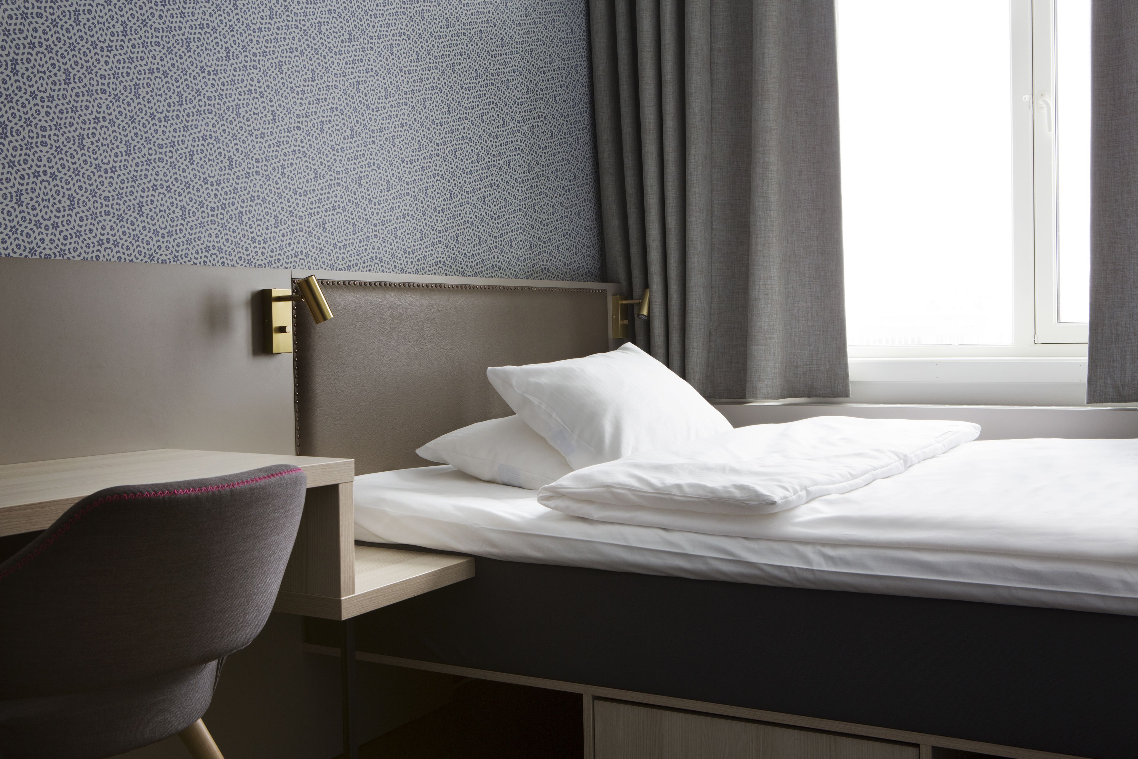 A hotel room with a bed, a desk, and a chair.