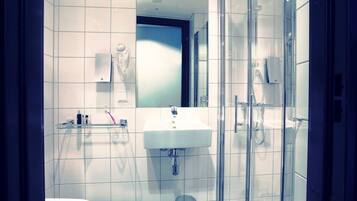 A modern bathroom with a glass shower enclosure, a white sink, and a toilet.