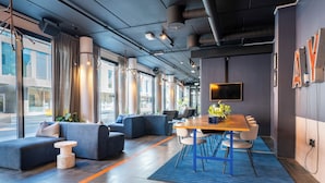 A modern interior with a long table, blue sofas, and a large window. - Comfort Hotel Xpress Tromso (Tromsø)