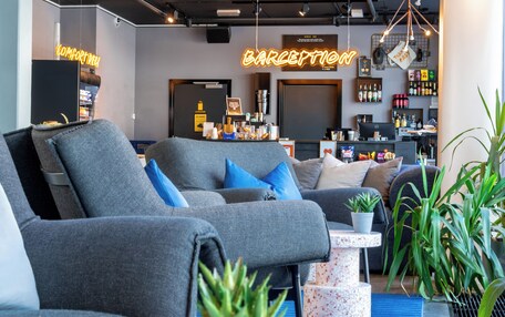 A modern lounge area with grey sofas, a coffee machine, and a bar area.