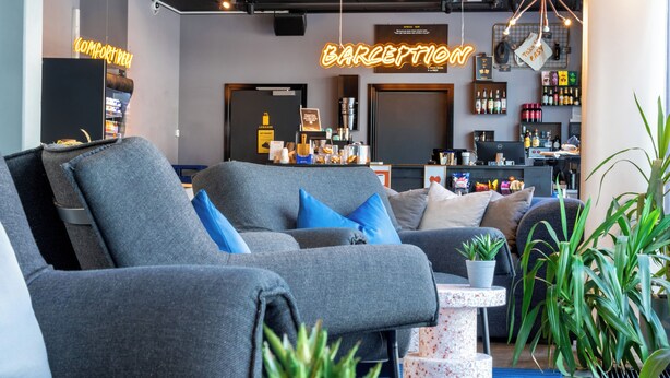 A modern lounge area with grey sofas, a coffee machine, and a bar area. - Comfort Hotel Xpress Tromso (Tromsø)