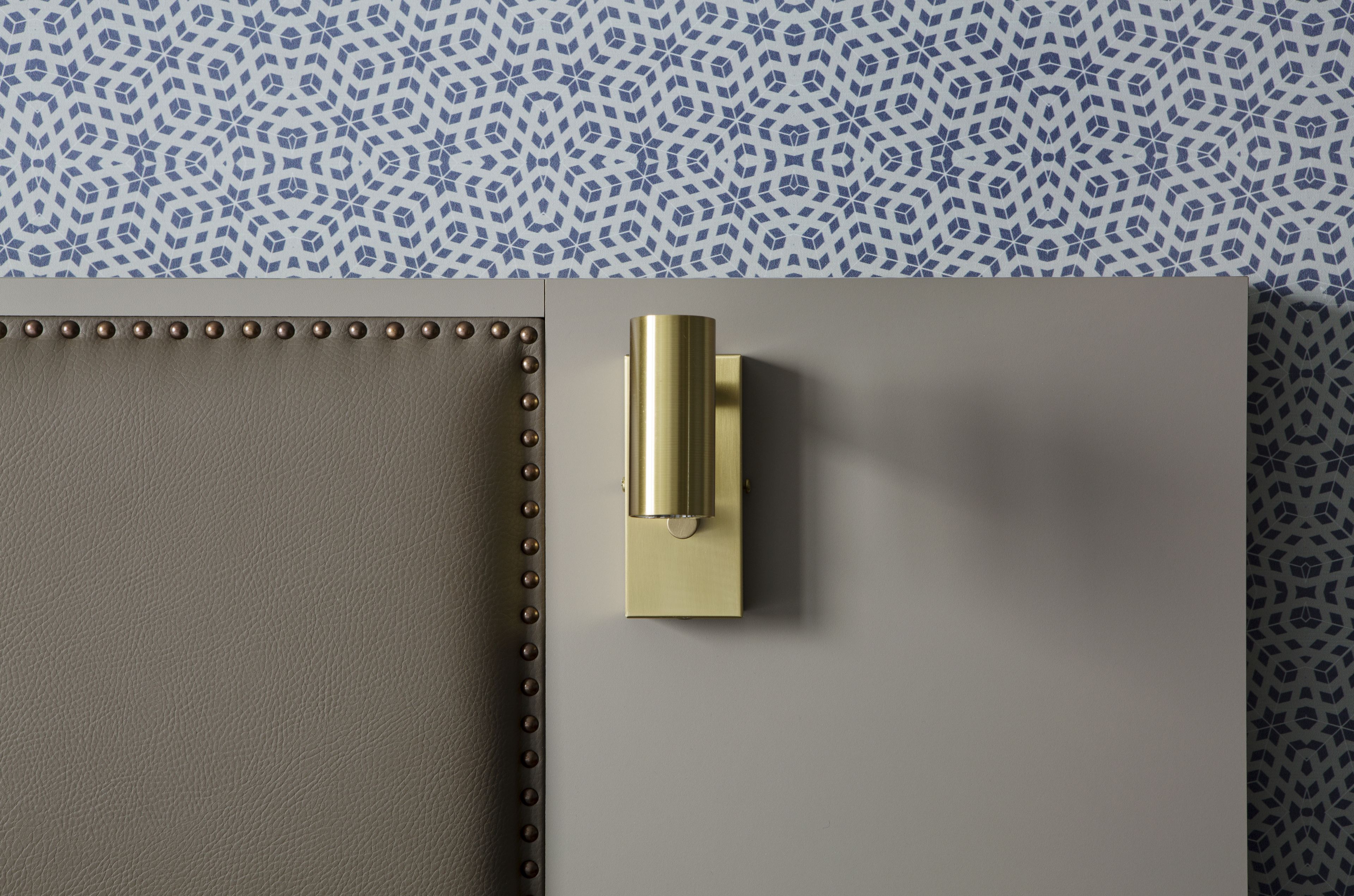 Un objeto metálico sobre una superficie gris con un fondo azul y blanco estampado.