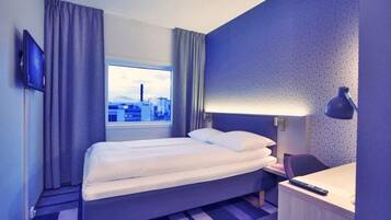 Ein Hotelzimmer mit Bett, Schreibtisch, Lampe und Fernseher.