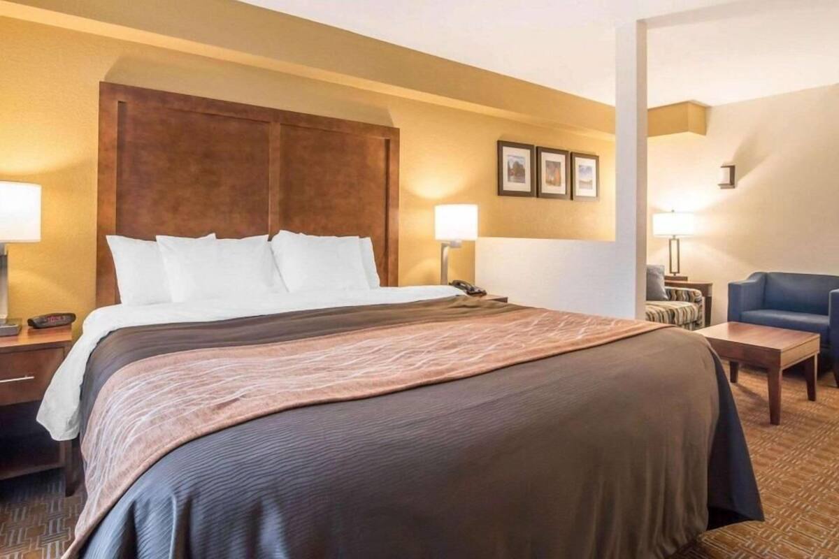 A hotel room with a large bed, two bedside tables, a desk, a chair, and a wall-mounted TV.